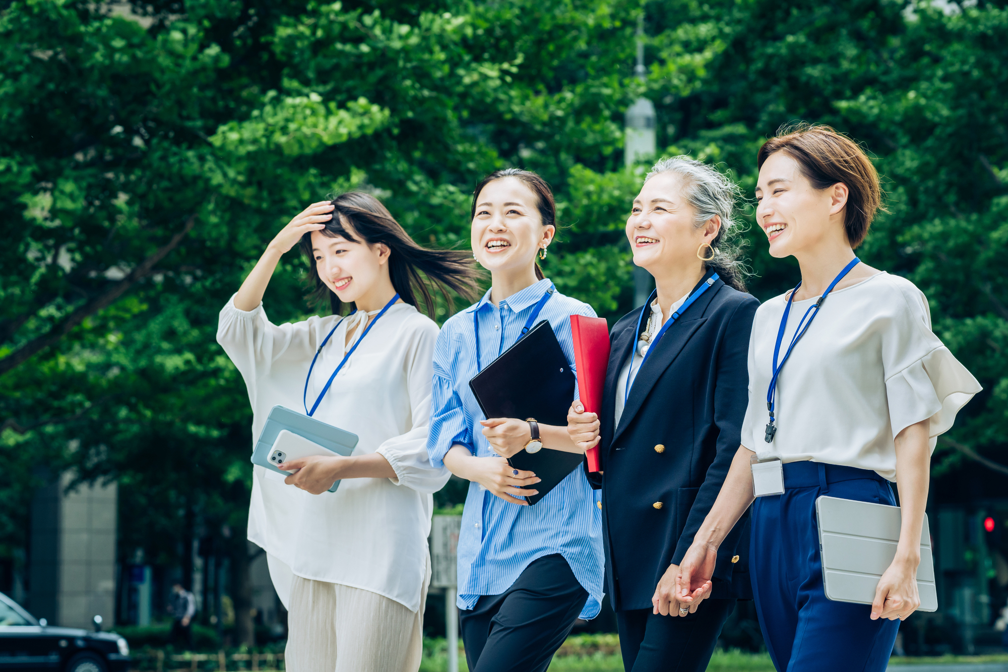 さまざまな世代の女性ビジネスパーソン4人が歩く様子