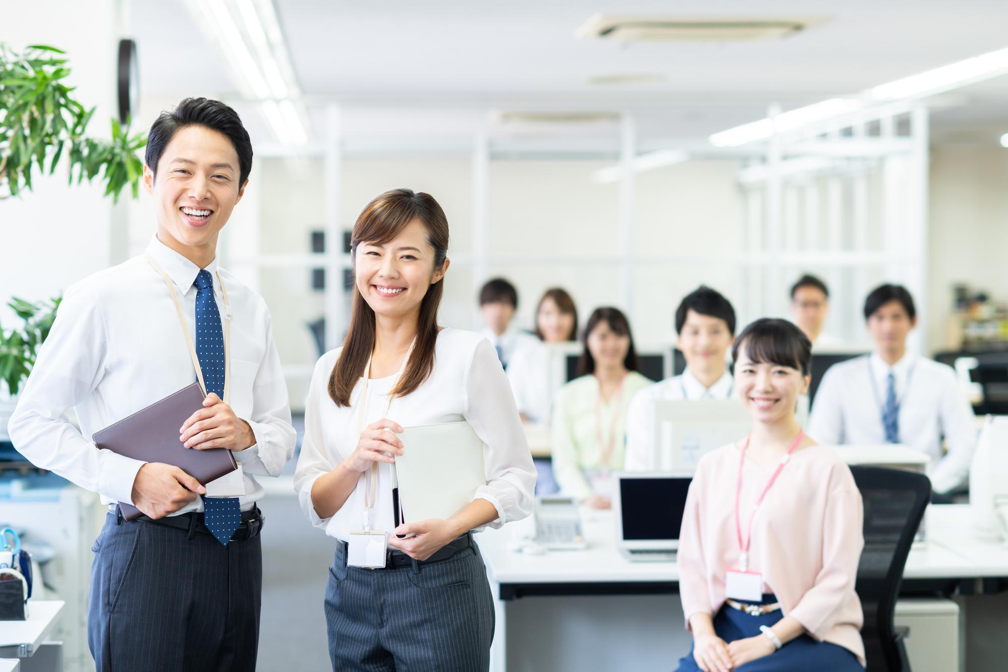 オフィスのような場所で、笑顔でこちらを見る多数の人たち