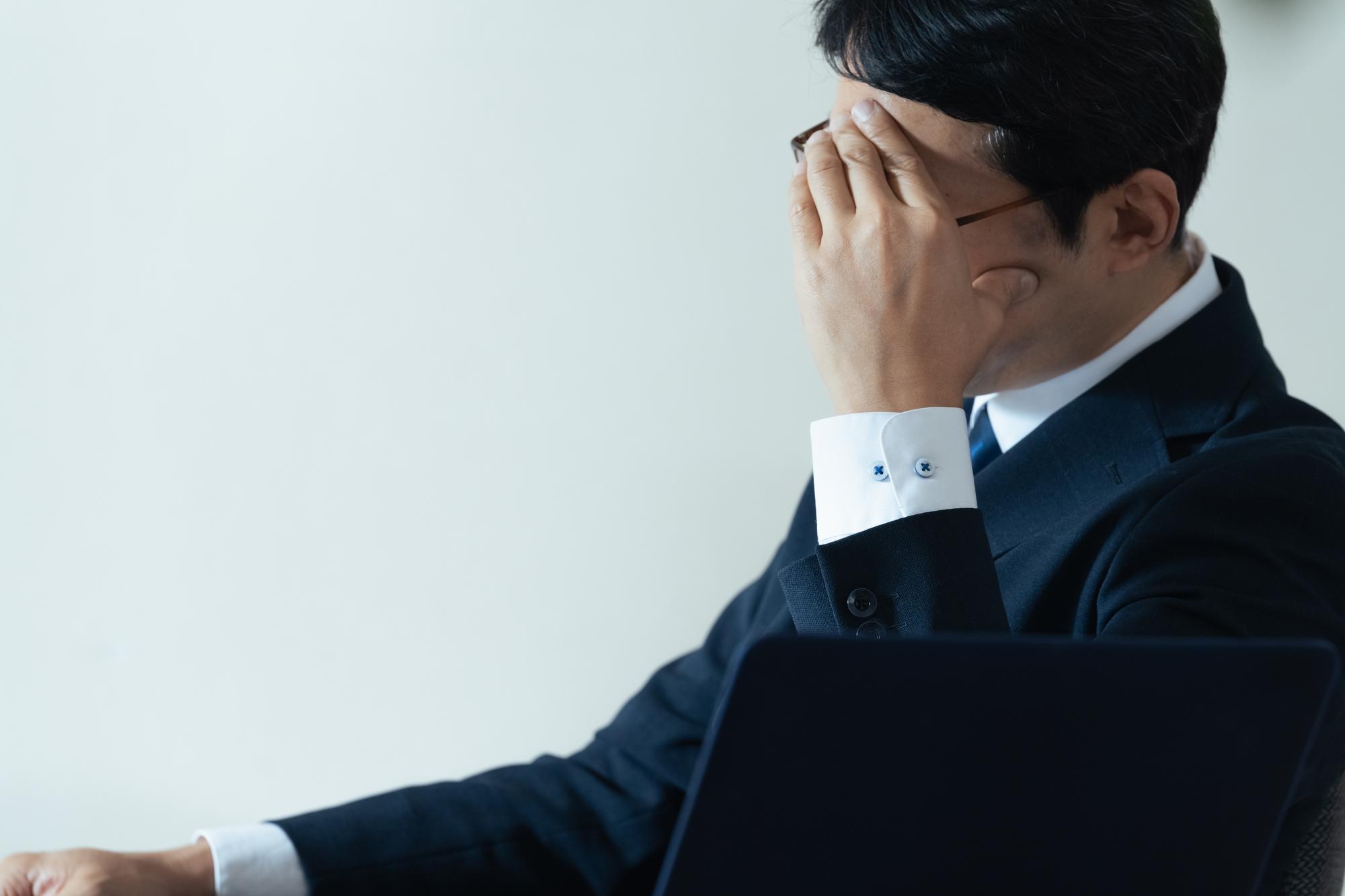 頭を抱えるスーツを着た男性