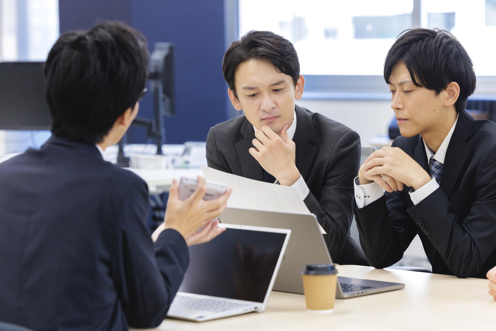 真剣な表情でミーティングしている様子のスーツを着た3人の男性