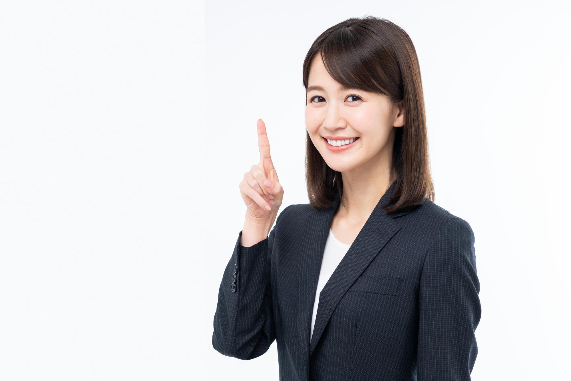人さし指を立てている、カメラ目線のスーツを着た女性