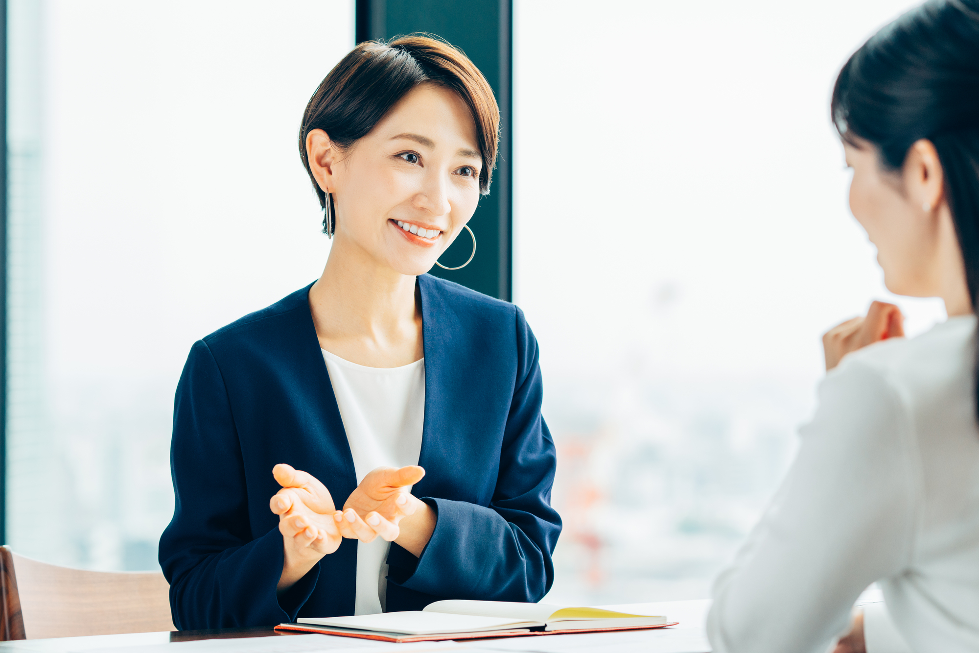 女性に向かって説明する女性ビジネスパーソン