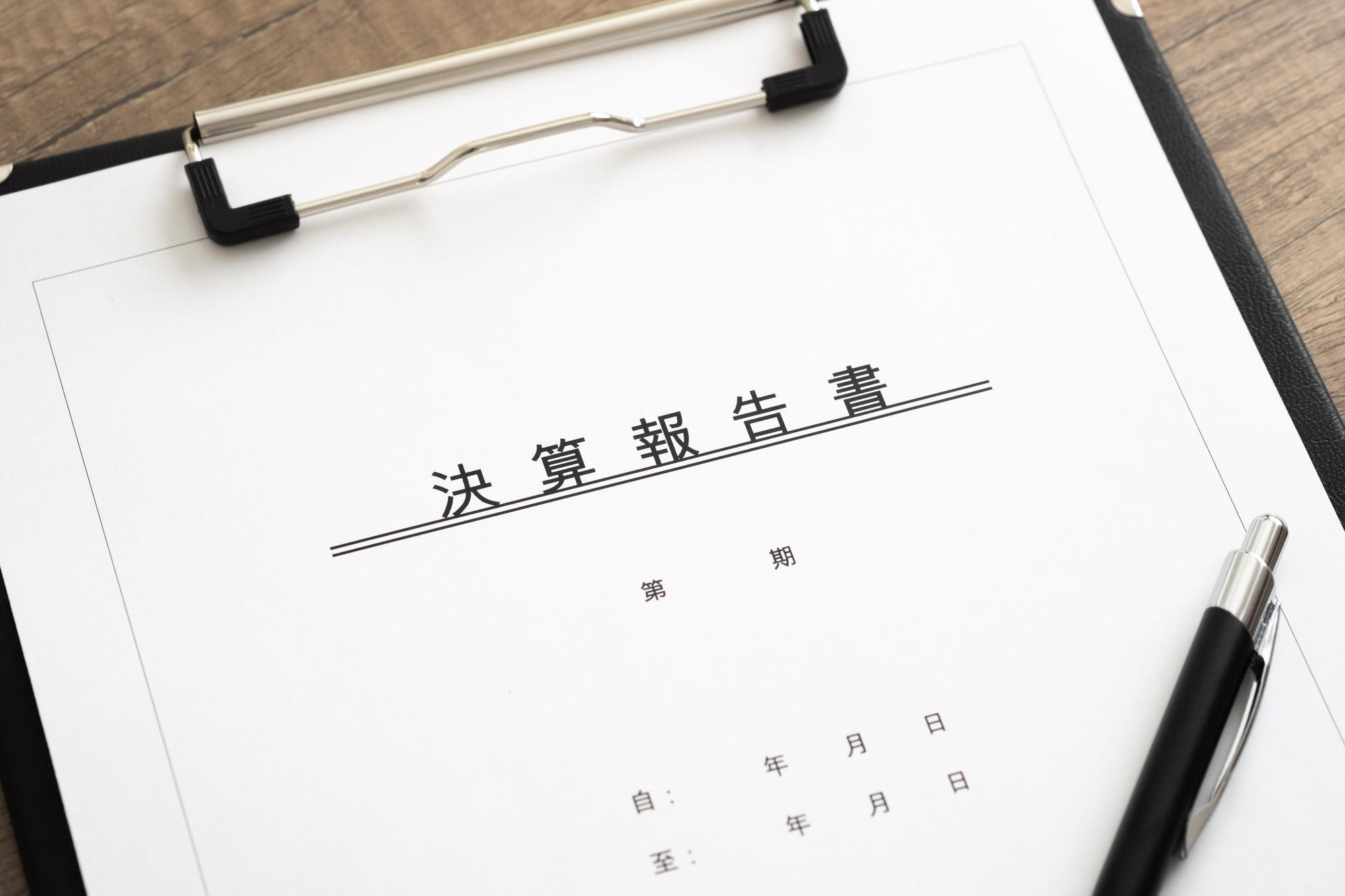 バインダーに挟んだ決算報告書と書かれた紙とペン