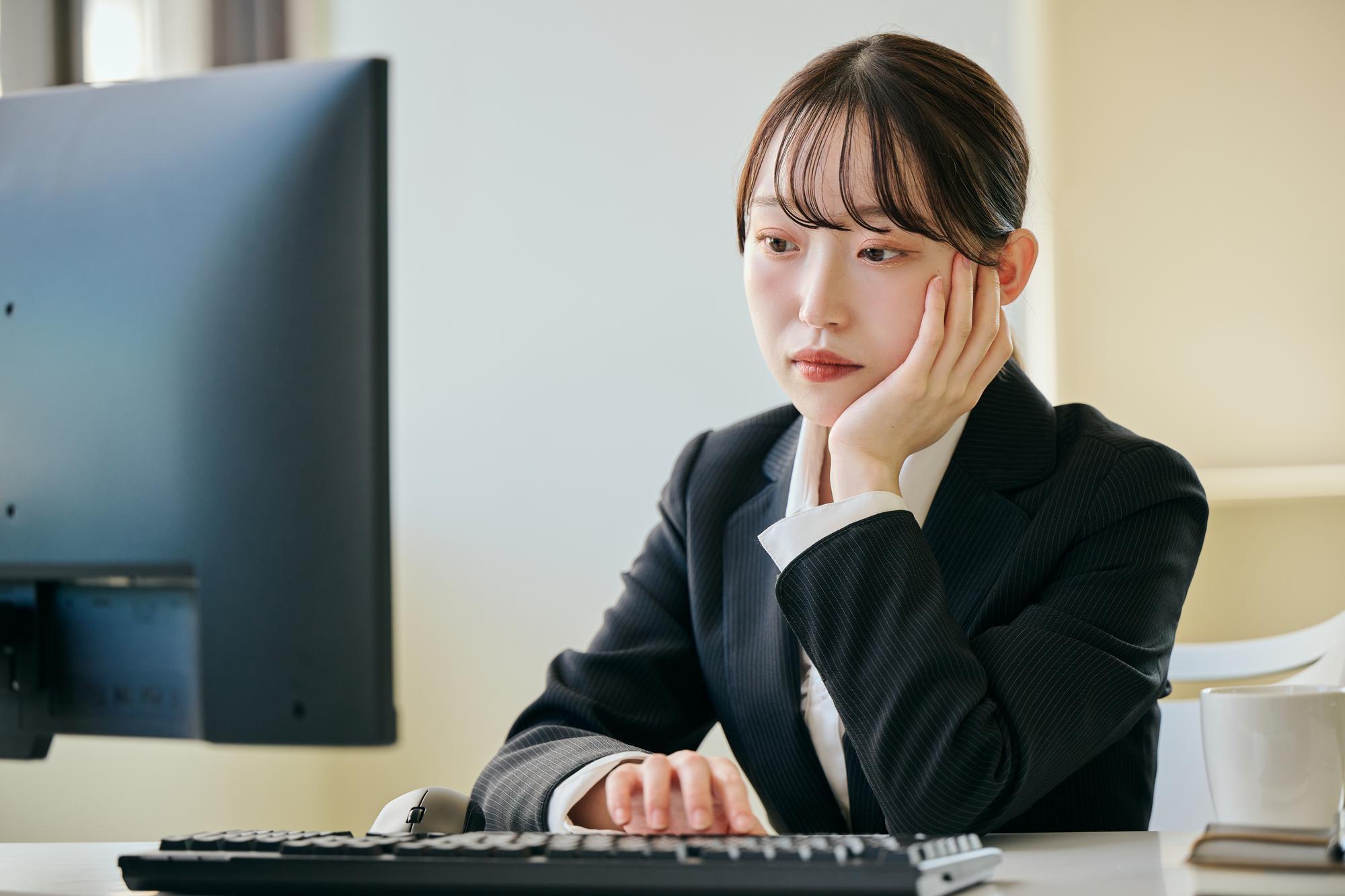 パソコンの前で頬づえをつく女性