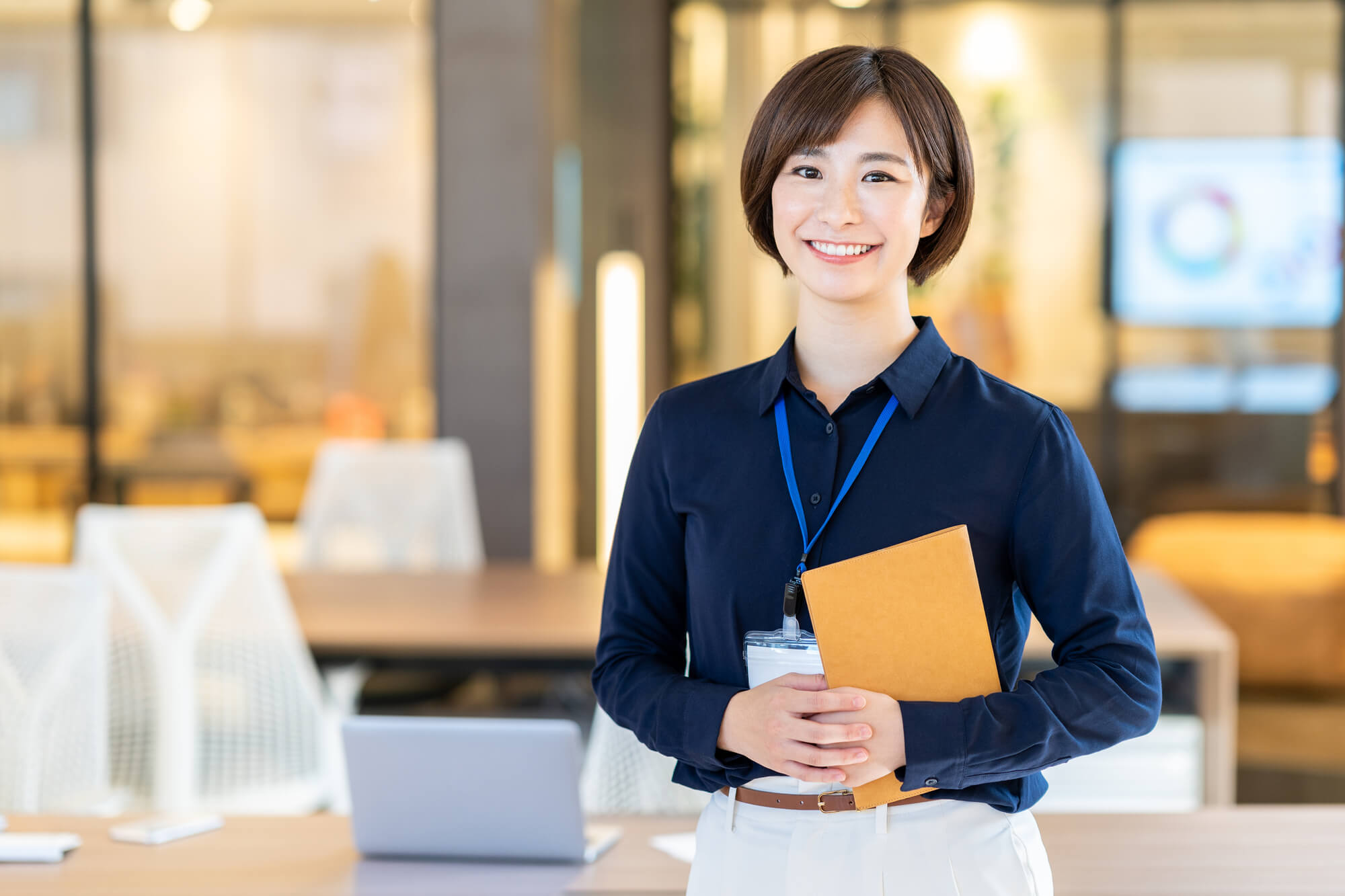ノートを手に笑顔を見せる女性ビジネスパーソン