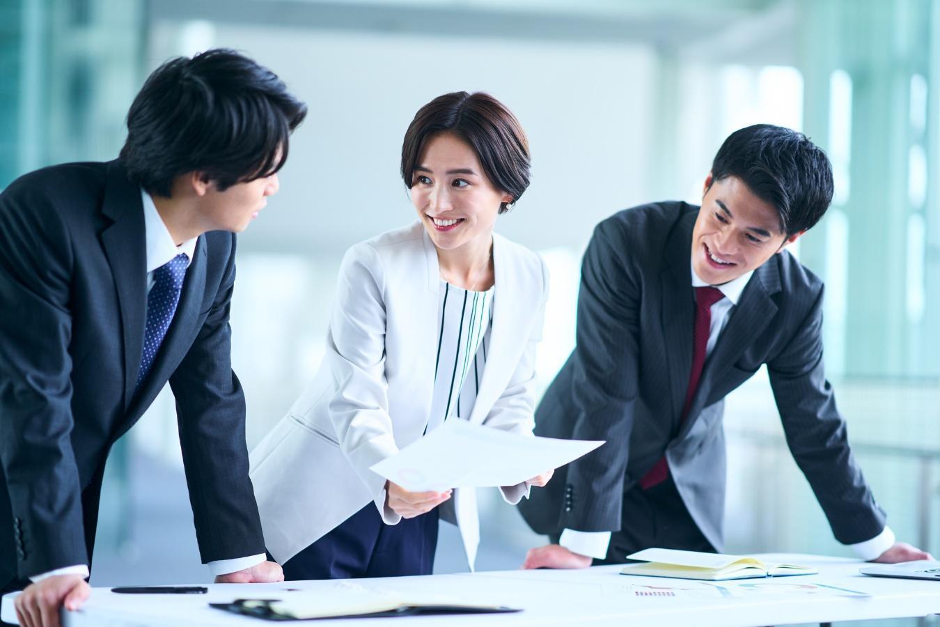 資料を見ながら笑顔で話し合う3人の男女