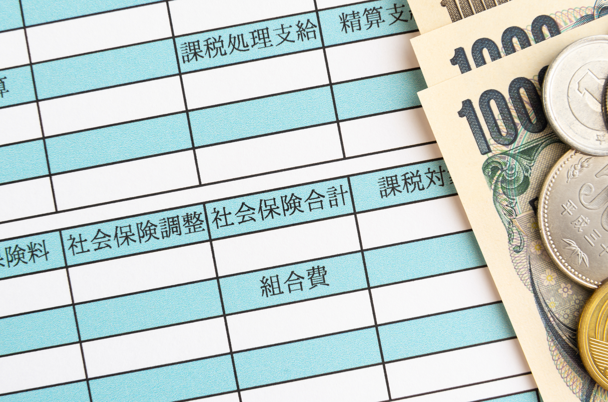 給与明細の社会保険料部分と紙幣、硬貨