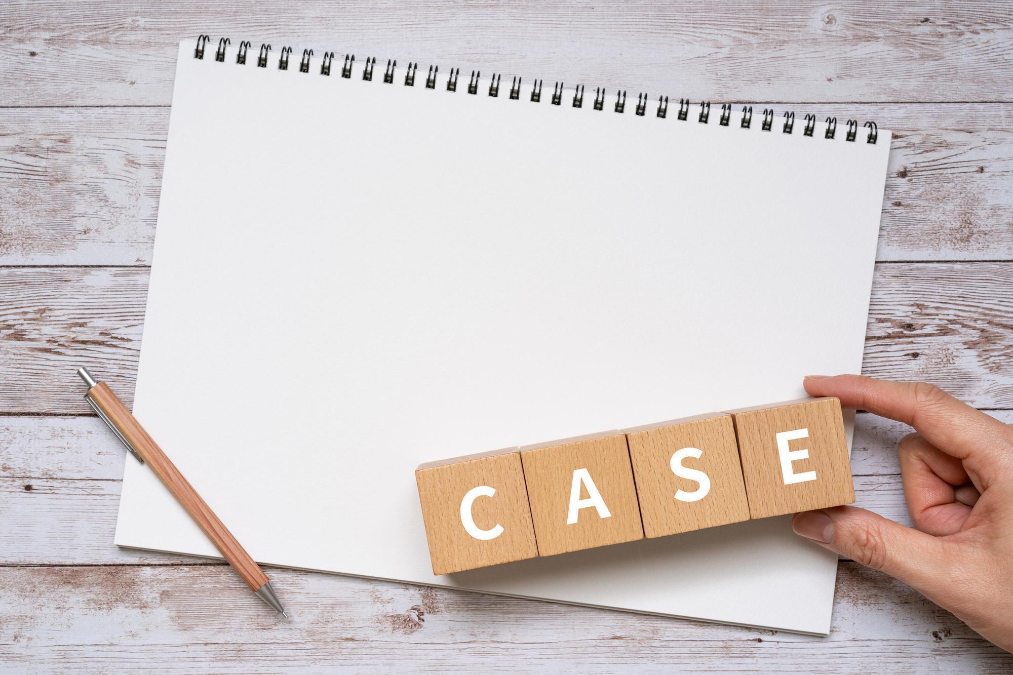 スケッチブック、CASEと書かれた木のブロックを持つ手、ペン