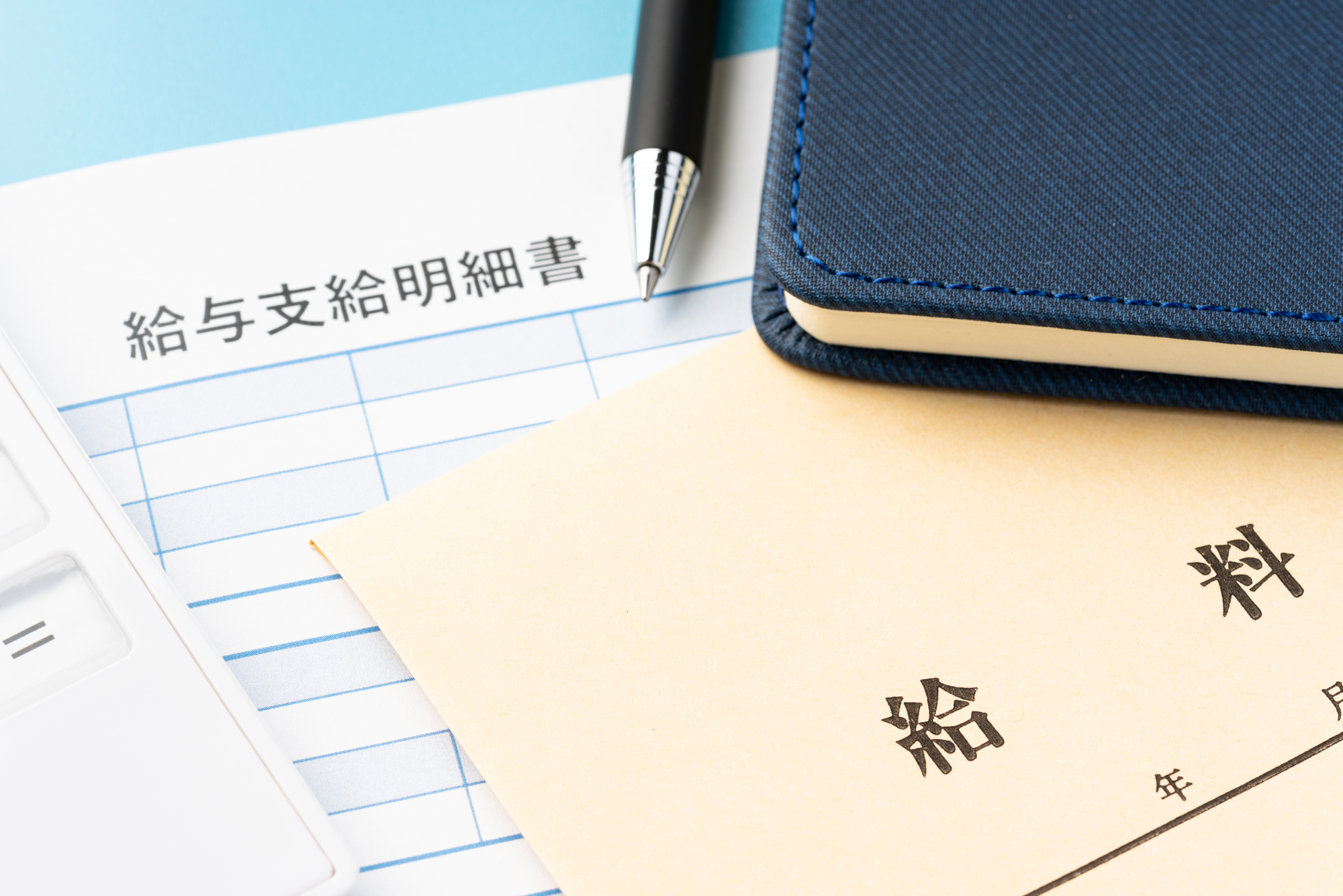 給与明細書と封筒・ペン・手帳