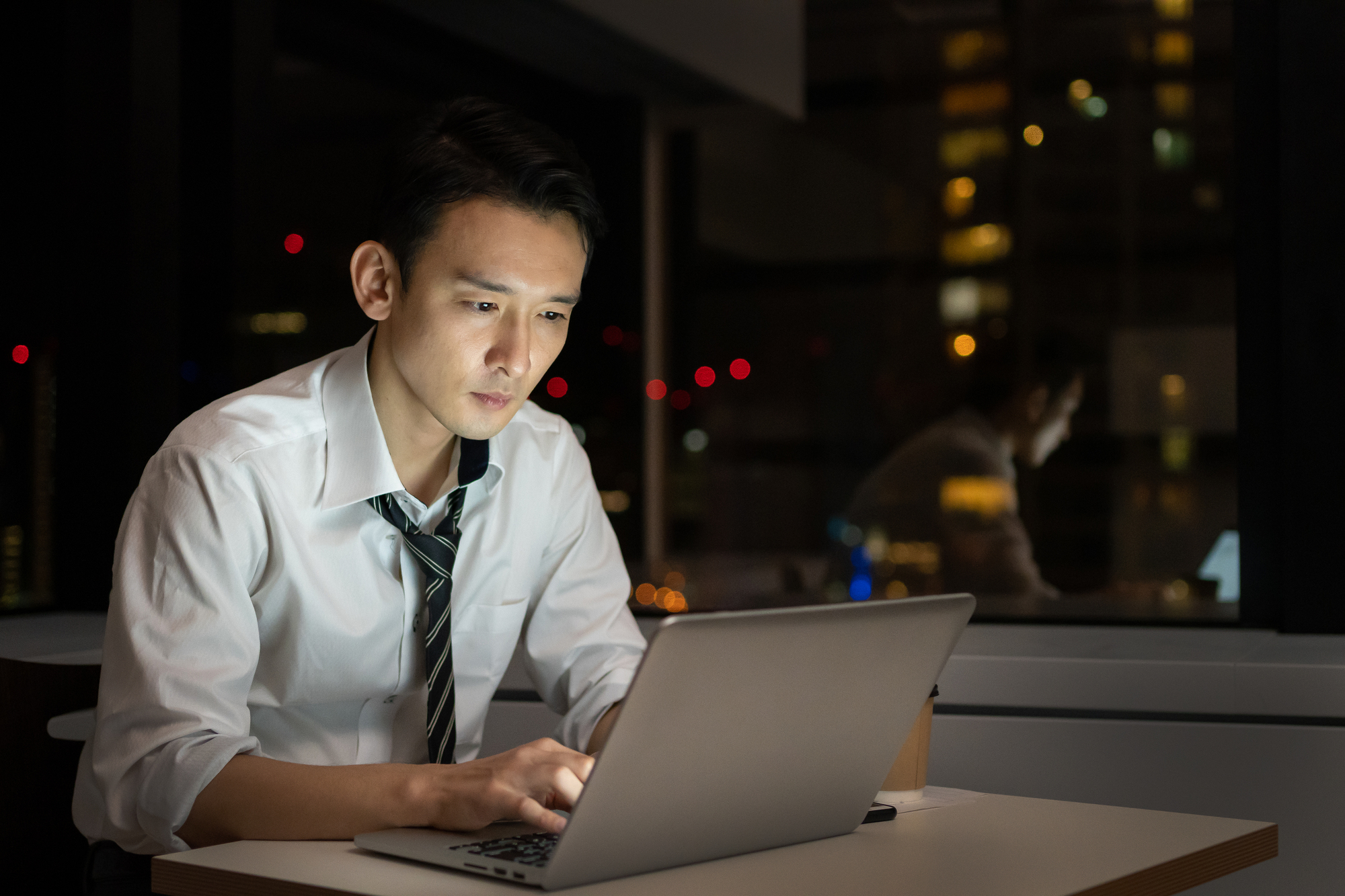 オフィスで夜遅くまで残業をするビジネスパーソン