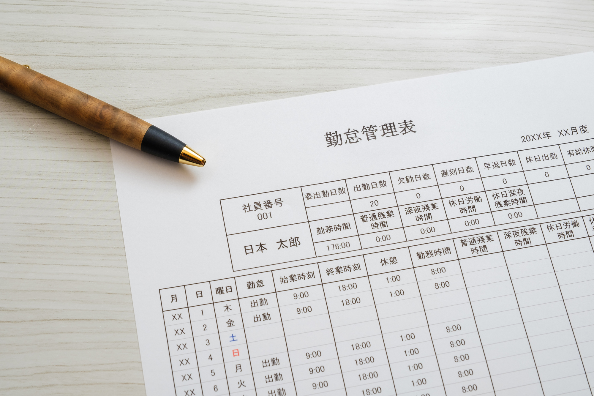 紙の勤怠管理表とペン